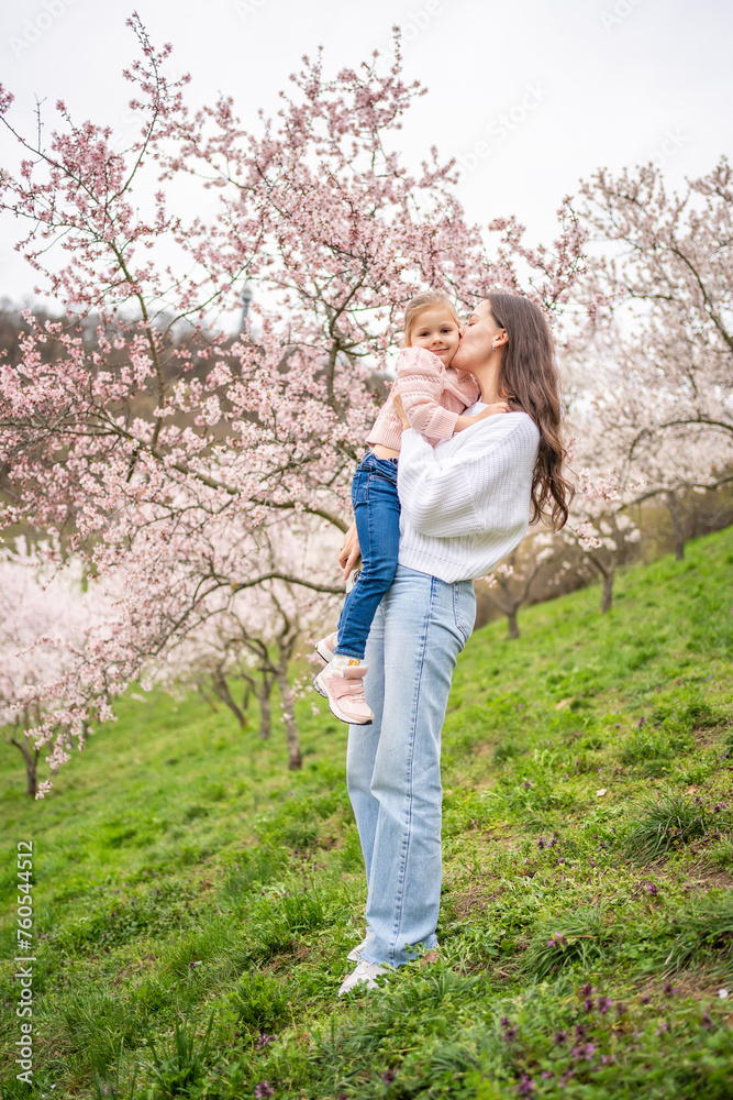 Young woman with little daughter in a blooming pink and white garden Petrin in Prague, spring time in Europe Young woman with little daughter in a blooming pink and white garden Petrin in Prague, spring time in Europe