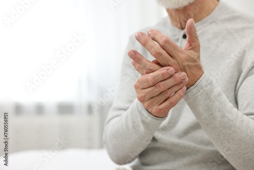 Arthritis symptoms. Man suffering from pain in hand at home, closeup. Space for text