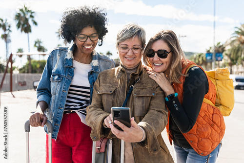 Three women tourist friends using cell phone, traveling enjoying weekend vacation photo