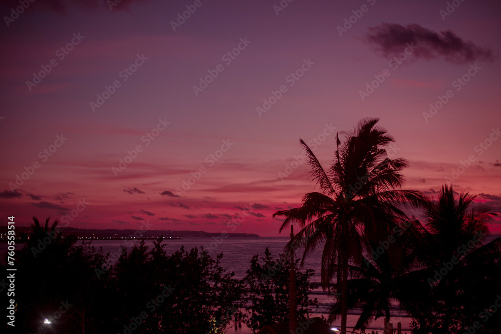 Bright red sunset against the background of the ocean and palm trees. Amazing beautiful sunset on the islands. Colorful natural background