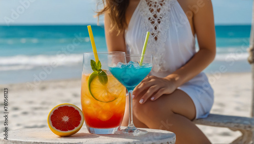 A girl sits with a cocktail on the beach on a sunny day.