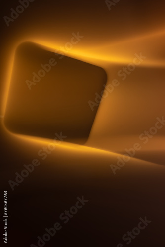 Abstract glowing square with smooth lines in yellow-orange colors on a black background. Vertical orientation. Copy space