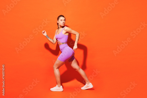 Full body side profile view young fitness trainer woman sportsman wear top shorts purple clothes train in home gym jogging look aside isolated on plain orange background Workout sport fit abs concept