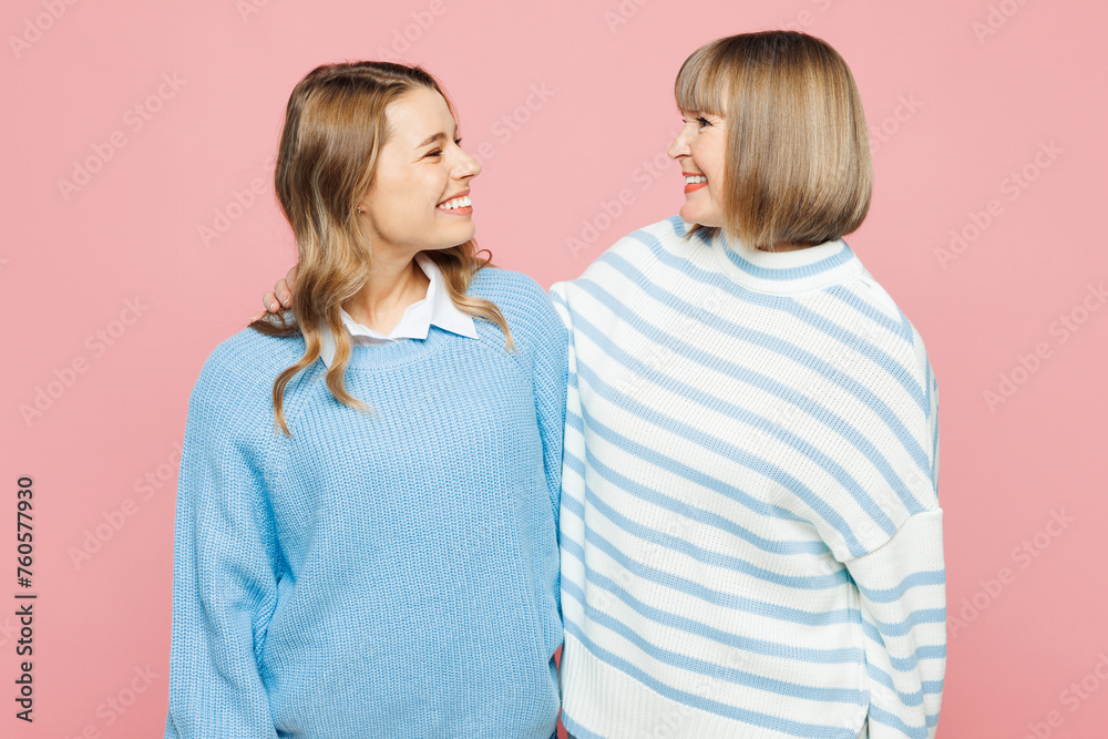 Elder smiling happy parent mom 50s years old with young adult daughter two women together wear blue casual clothes hug look to each other isolated on plain pastel pink background. Family day concept. Elder smiling happy parent mom 50s years old with young adult daughter two women together wear blue casual clothes hug look to each other isolated on plain pastel pink background. Family day concept.
