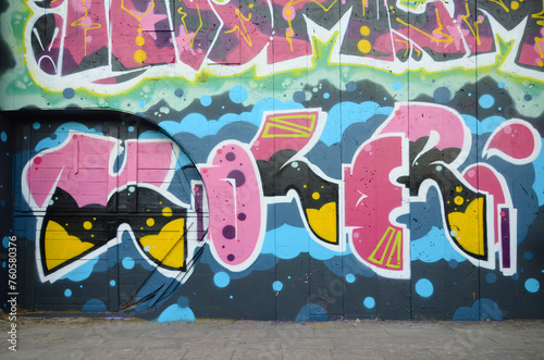 The old wall decorated with paint stains in the style of street art culture. Colorful background of full graffiti painting artwork with bright aerosol outlines on wall. Colored background texture