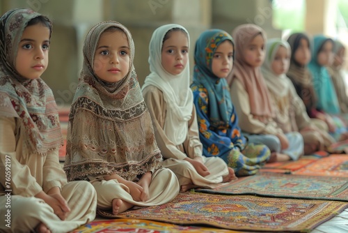 Cute arabic girls in traditional Islamic attire sit cross-legged on colorful prayer rugs  listening verses from the Quran from their teacher. Muslim faith and religion concept