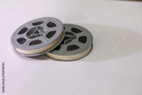 Two old school 8mm film reels against a white background with a shadow falling to the right. 