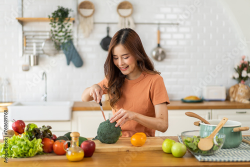 Portrait of beauty body slim healthy asian woman eating vegan food healthy with fresh vegetable salad in kitchen at home.diet, vegetarian, fruit, wellness, health, green food.Fitness and healthy food