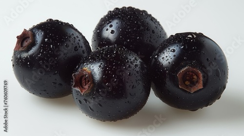  a group of black plums sitting on top of each other on a white surface with drops of water on them.