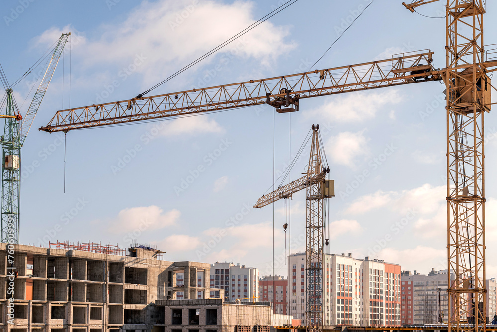 The construction process of a multi-storey residential building, construction cranes, a house under construction.