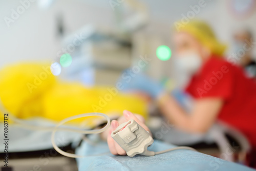 Checking up oxygenation with fingertip pulse oximeter during surgery in operating room in clinic. Saturation blood of oxygen. Monitoring of the patient condition