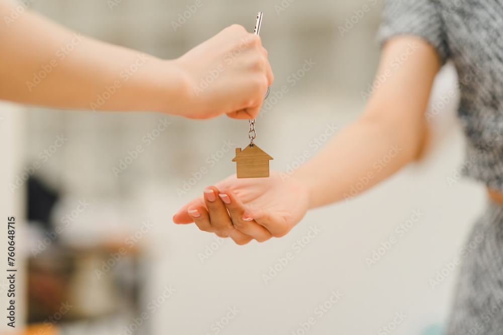 Obraz premium Close-up of a hand giving a house key to another, symbolizing property transfer or rental agreement.