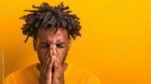 Close up studio portrait of young African man sneezing isolated on yellow background. Black male suffering from seasonal allergy. Rhinitis, symptoms of cold, flu, virus concept.
