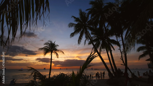 Sunset on beach with people and palms
