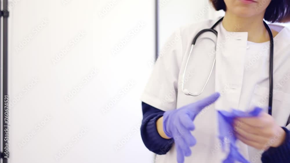 Unrecognizable female doctor putting on latex gloves in a clinic Unrecognizable female doctor putting on latex gloves in a clinic