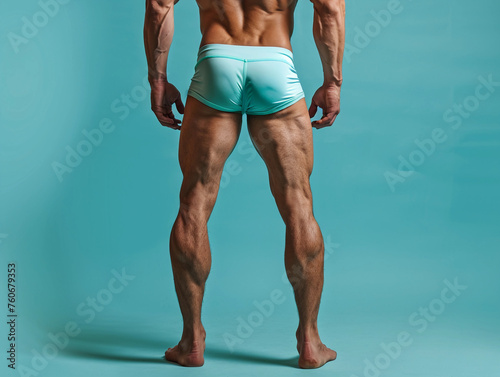 Back view of muscular fitness male model legs wearing underwear on colored background 