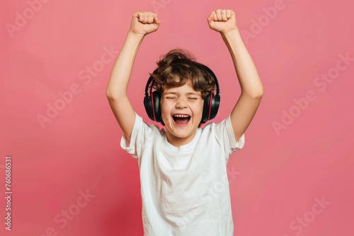 Happy child boy in headphone streamer playing video game with winner expression solid color background