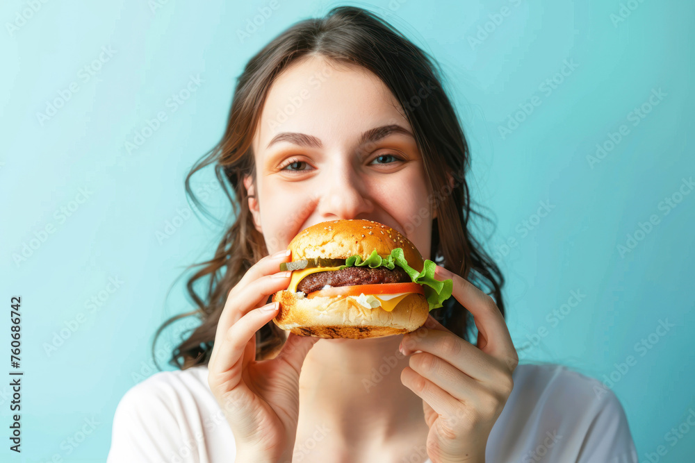 portrait of woman eating delicious cheeseburger on color background