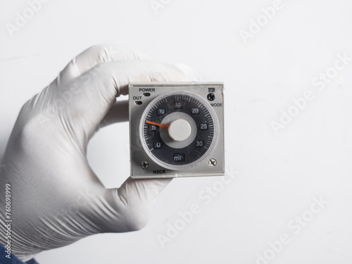 Man's hand with gloves holds Electric  Timer H3CR isolated on white background. Electrical Equipment concept. photo