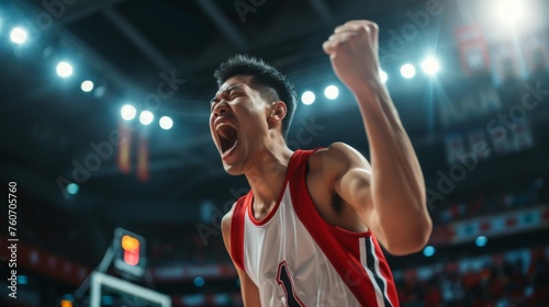 Asian basketball player celebrates victory, unleashing shouts of joy against the backdrop of a basketball stadium. Emotional celebration of winning the game © Vladimir