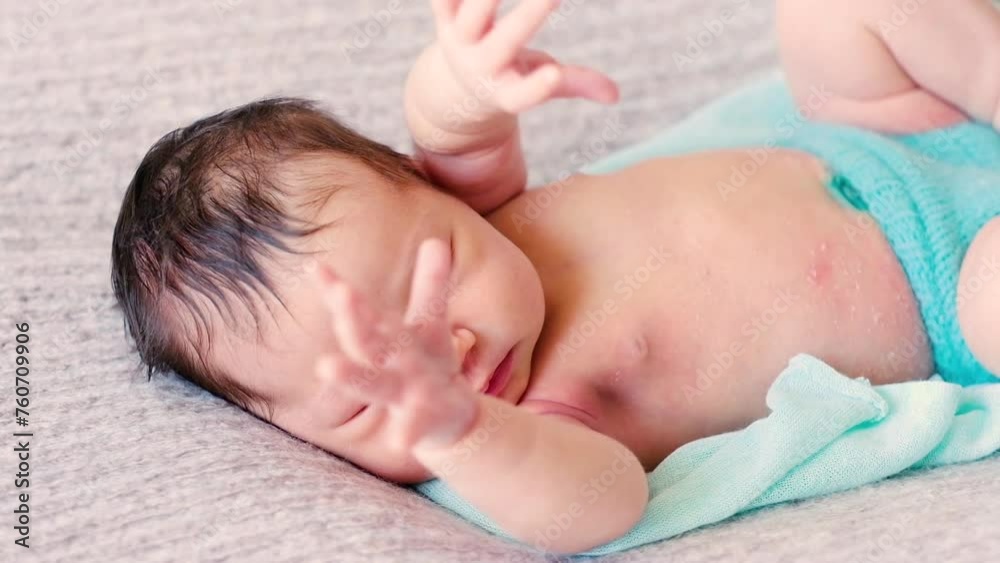 Beautiful newborn little baby with blue blanket, lies on bed and sleeps.