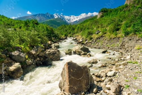 Stormy mountain river flowing among the stones against the backdrop of the extinct volcano Kazbek. North Caucasus. Russia