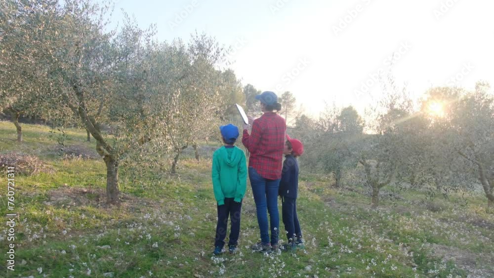 Farmer woman with her children visiting agricultural field and fruit trees with laptop tablet Farmer woman with her children visiting agricultural field and fruit trees with laptop tablet