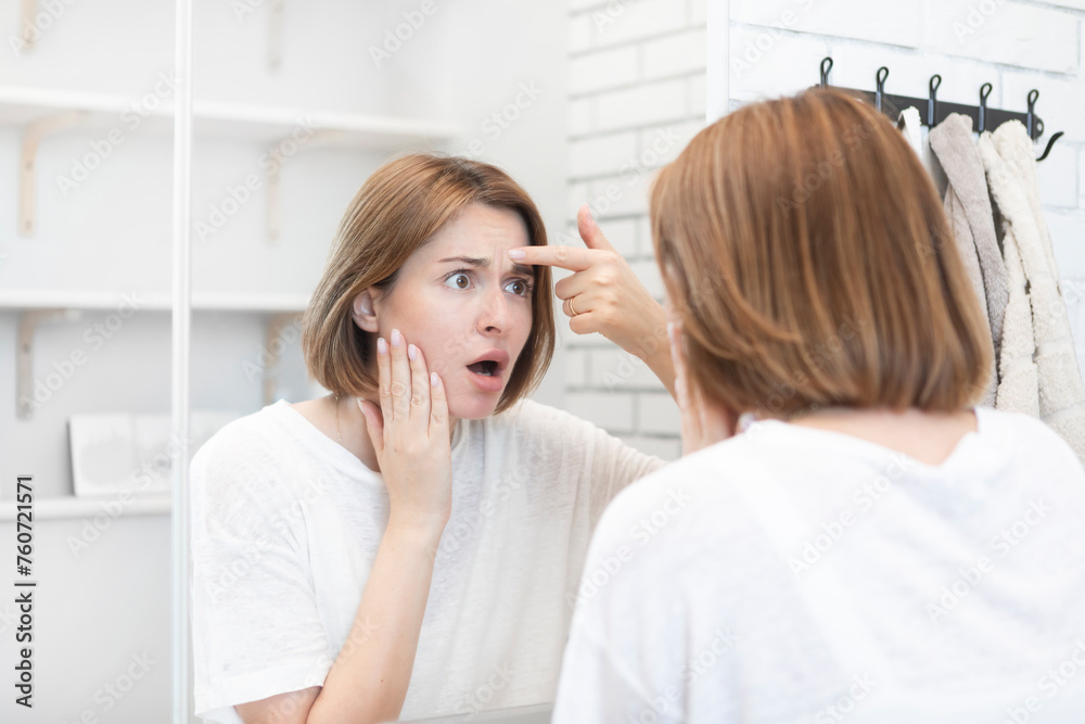 Young beautiful woman looking at mirror and confusing because of new wrinkles	