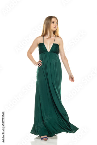 Full body front view portrait of elegant lovely blond lady walking isolated on white background in green long dress