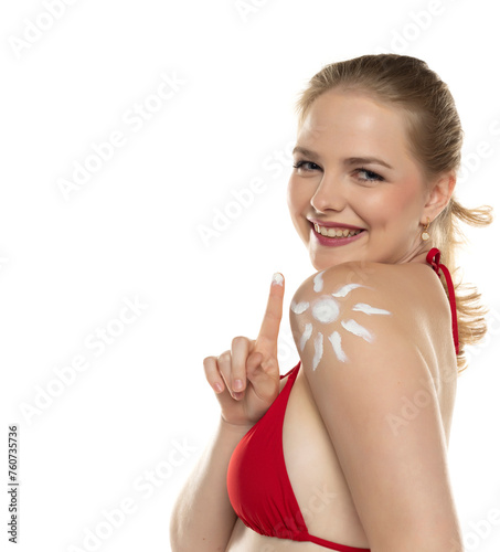 Beautiful smiling blond woman in red bra with cosmetic product in smile shape on her shoulder on white background.