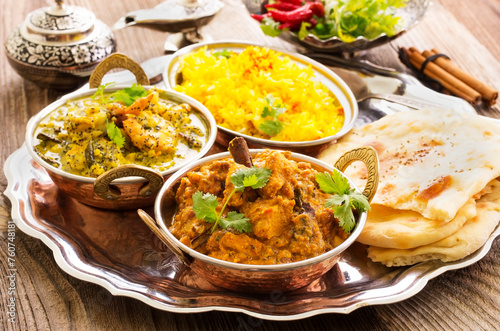 Traditional Indian curry dishes served with saffron rice and pita bread as close-up on a design plate