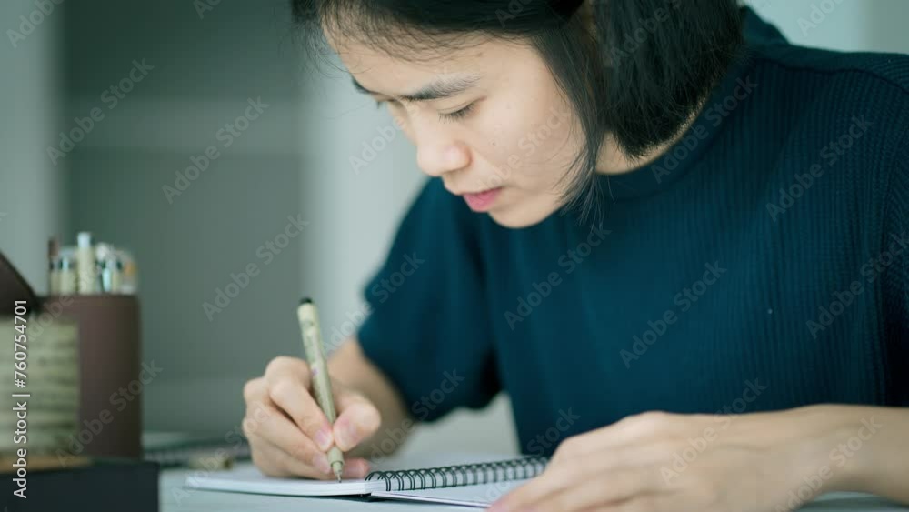 Woman writing down her thoughts on notebook at home, work space concept. Woman writing down her thoughts on notebook at home, work space concept.