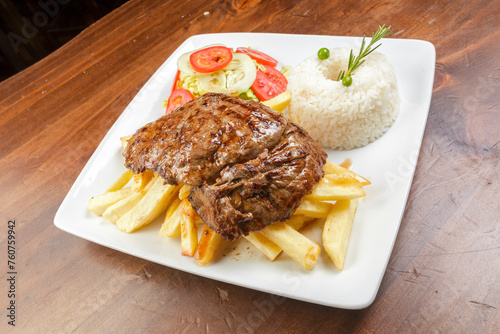 A plate of food with a piece of Beff steak and french fries on it photo