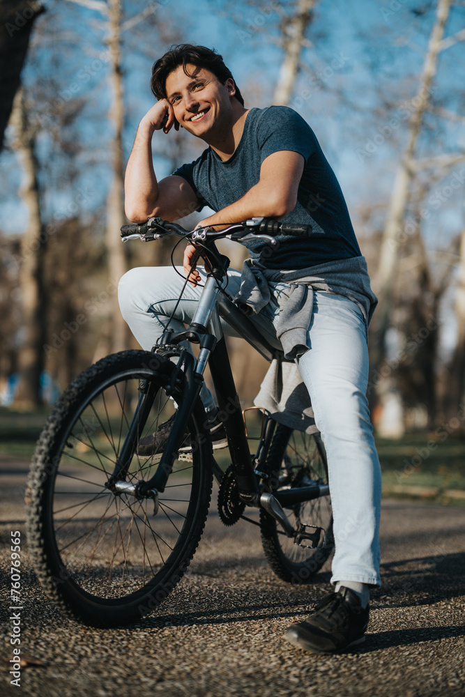 Obraz premium A happy man leans on his bike in a sunlit park, enjoying a leisurely outdoor activity on a clear day.