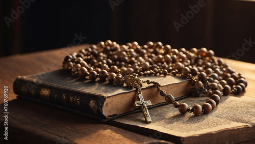 The Bible and wooden Christian rosary beads on dark background. Golden hour light