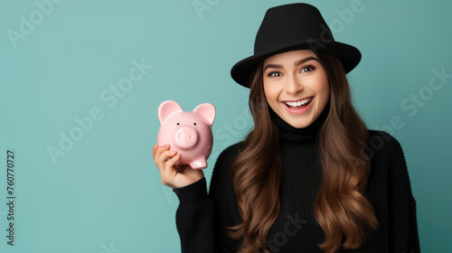 Smiling young girl holding a piggybank against blue background