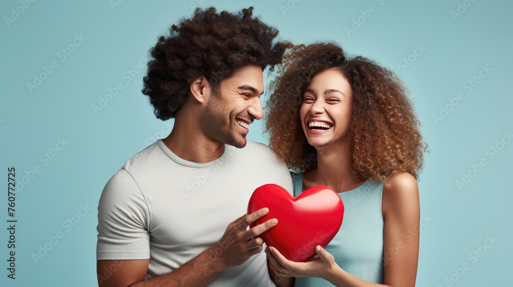 Cheerful man and woman closely facing each other, smiling joyfully while holding a red heart-shaped gift between them. Cheerful man and woman closely facing each other, smiling joyfully while holding a red heart-shaped gift between them.