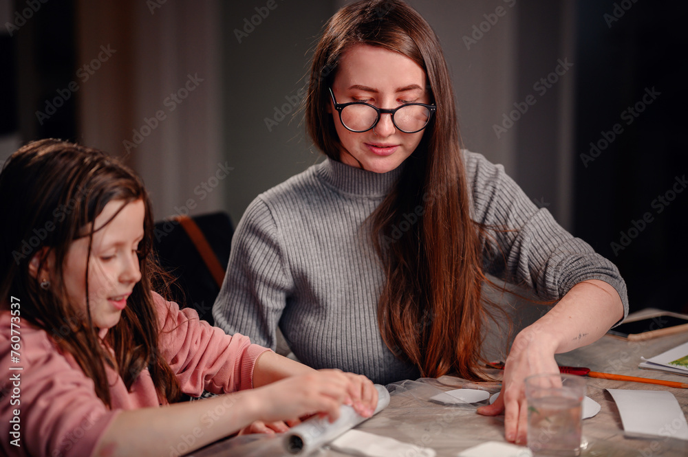 An engaging scene of a girl and a woman working together on a crafts project, with their hands busily at work amid various materials