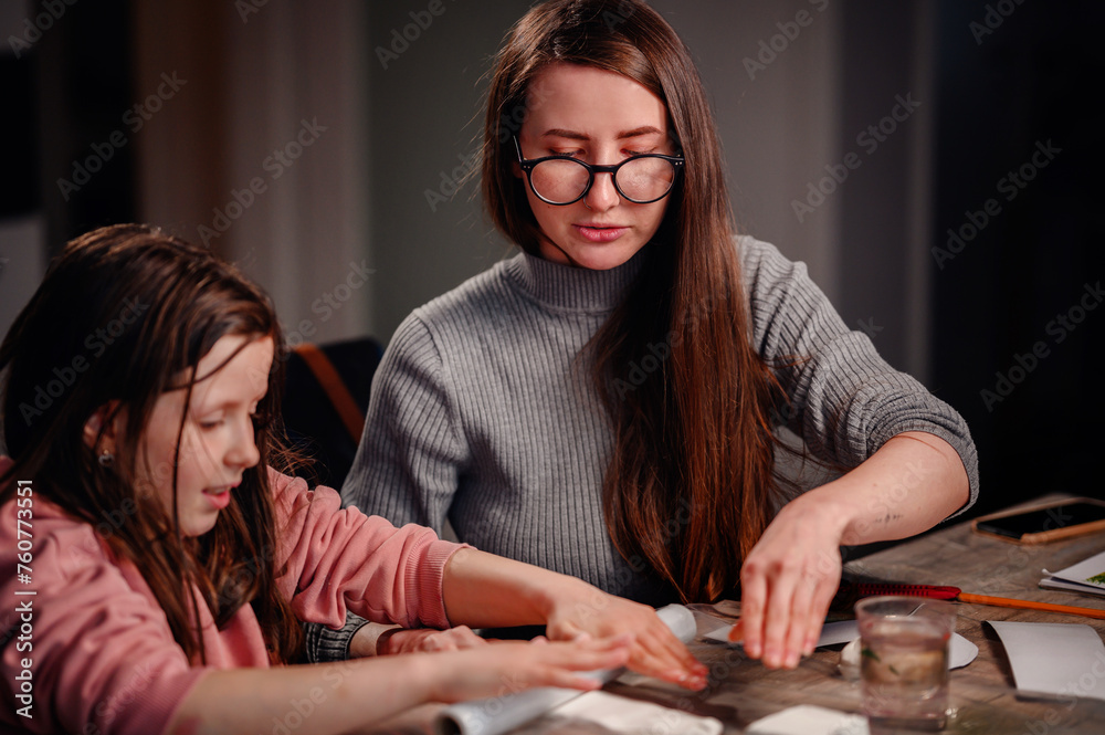 An engaging scene of a girl and a woman working together on a crafts project, with their hands busily at work amid various materials