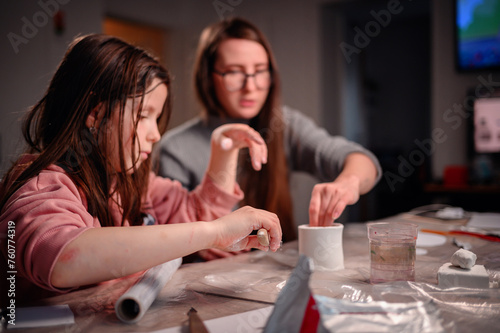 A girl and a woman are absorbed in creating a craft with clay, a dynamic scene of family interaction and joint creativity at home
