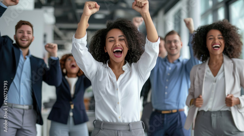 Joyful office workers are celebrating a success with their hands raised in the air and big smiles on their faces in a bright, modern office space. photo