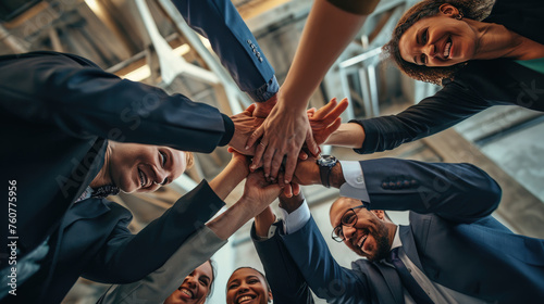 Low-angle view of a diverse group of professionals engaged in a team-building exercise, where they join their hands together in a show of unity and cooperation.