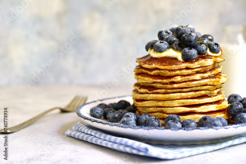 Stack of fresh hot pancakes with maple syrup and blueberries.