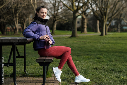 Sport young woman relaxing on a bench in a park.