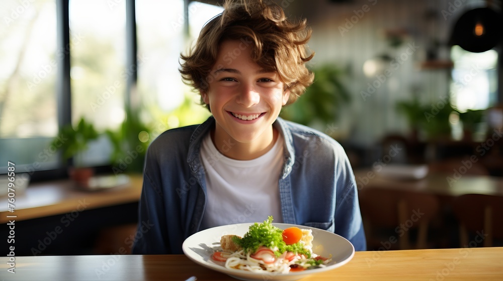 Happy boy sitting at a table with a plate of food having lunch at home. Young boy in casual clothes preparing to eat lunch while smiling and looking at the camera. Cheerful boy getting ready to eat.