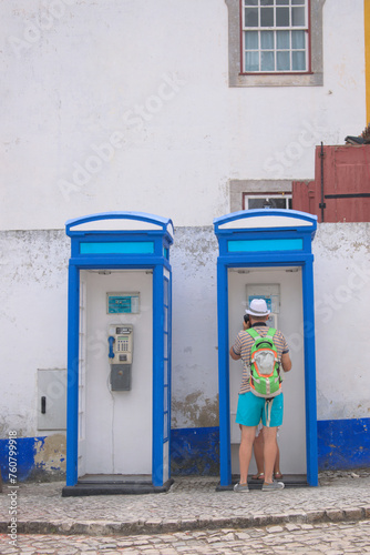 Bright blue phone cabin being used by a tourist in the mediterranean