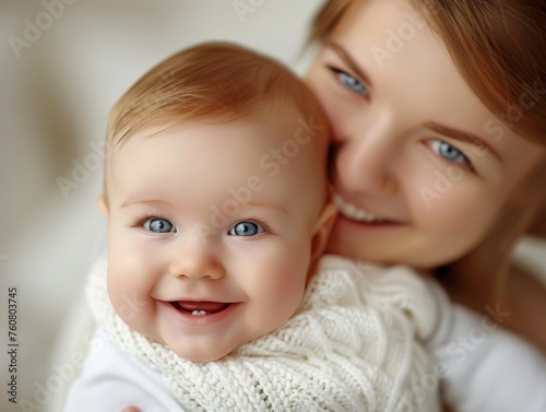 A young woman with her baby snuggled close to her chest, both of their faces are alight with joy