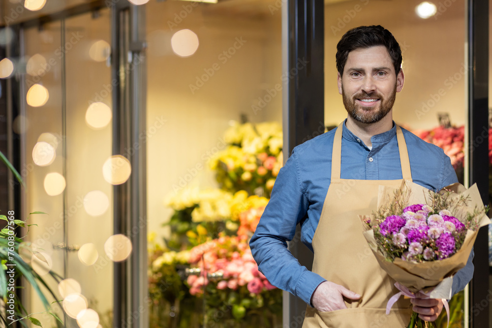 Cheerful male florist holding a beautiful bouquet, ready to greet customers at the entrance of his well-lit flower shop.