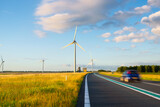 Landscape during sunset with road, field and wind turbines. Windmills for energy production. Green energy in the Netherlands. A beautiful asphalt road with wind power turbines during sunset.