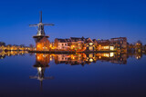 The windmill De Adriaan, Haarlem, Netherlands. Historic buildings. Cityscape during the blue hour. Reflections on the surface of water. Panorama. Picture for background and wallpaper.